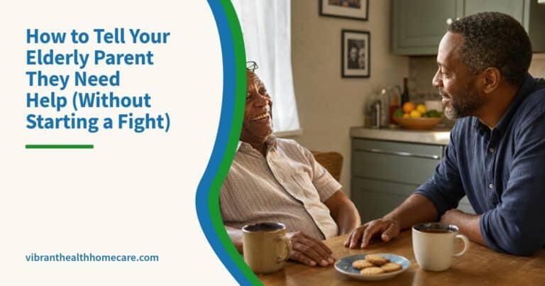 An older man and his adult son talk over tea at a sunny kitchen table, both relaxed and smiling.